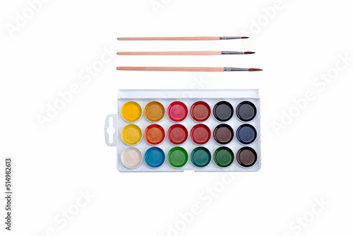 Multicolored aquarelle paints in paint box with brushes on white background.