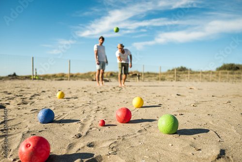 Sticker Tourists play an active game, petanque on a sandy beach by the sea - Group of yo