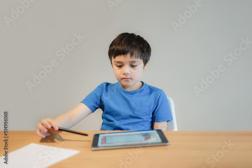School kid studying online with teacher,Kid doing homework on tablet, Child boy using digital pad searching information on internet, Home schooling,E-learning online education,Children with technology