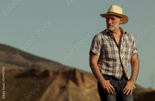 Portrait of adult man in sun hat and shirt in desert © WeeKwong