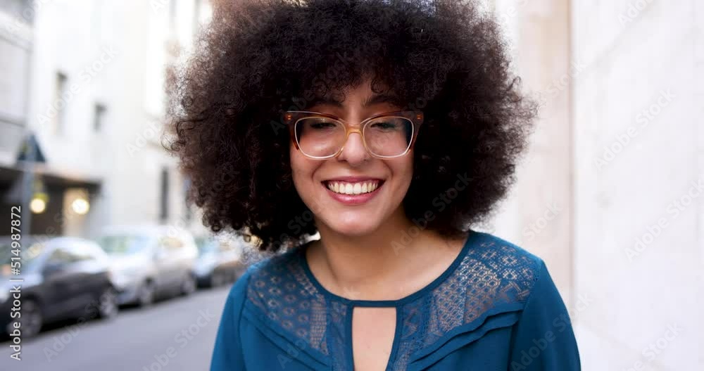 Woman with afro hairstyle and glasses smiling in the street Woman with afro hairstyle and glasses smiling in the street