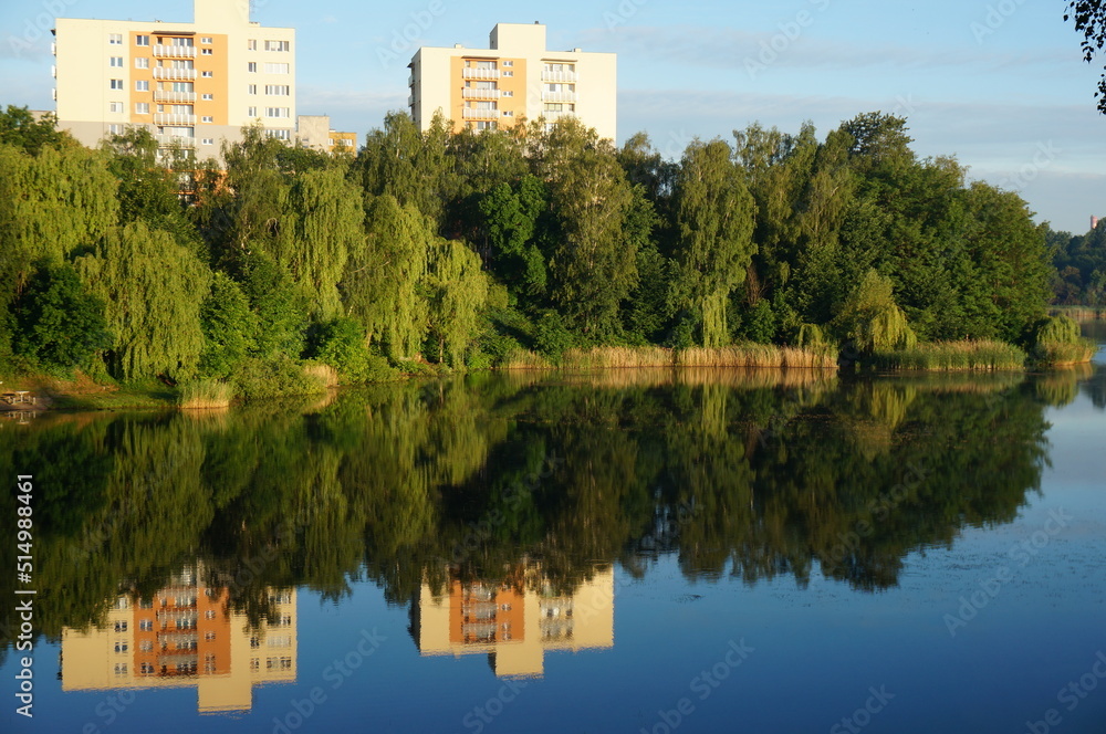 Reflection of multi-storey buildings in the water of Morawa pond. Szopienice neighbourhood, Katowice, Poland.