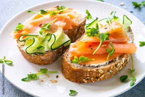 Open sandwich with cream cheese, salmon and cucumber in white plate. Healthy breakfast or snack. Close up.