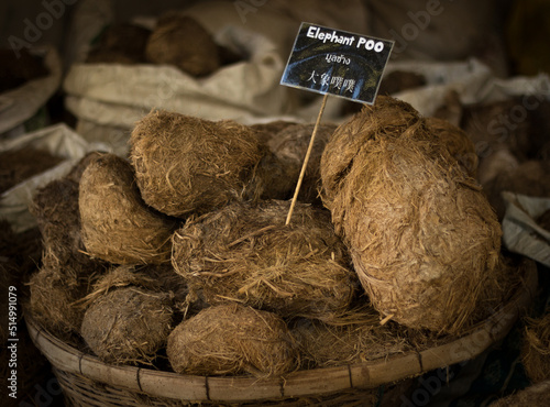 Photography Close up of dried elephant poo with a label on it written elephant poo in engl