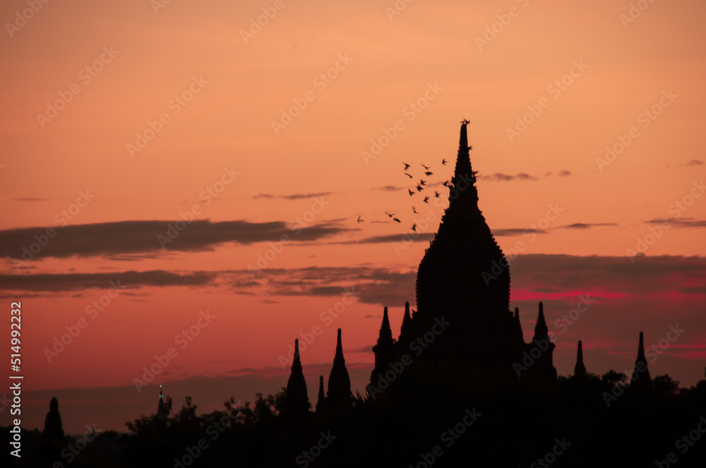 Sunset on a view of Thatbyinnyu temple pagoda in old Bagan, Myanmar with bird flying in the sky