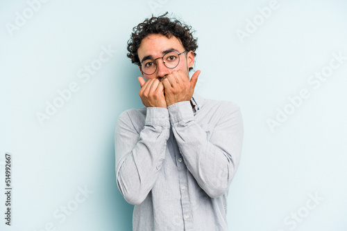 Young caucasian man isolated on blue background biting fingernails, nervous and very anxious.
