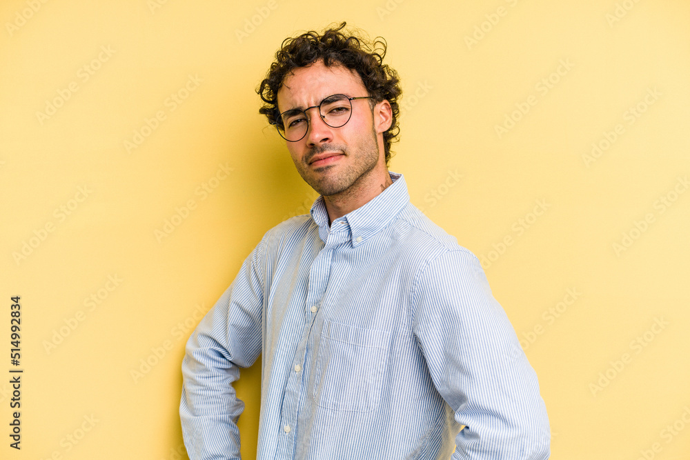Young caucasian man isolated on yellow background frowning face in displeasure, keeps arms folded. Young caucasian man isolated on yellow background frowning face in displeasure, keeps arms folded.