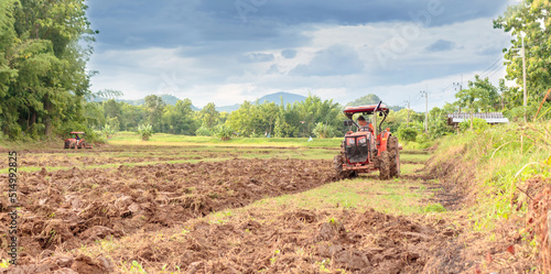 A farmer on a red tractor prepares the farmland.