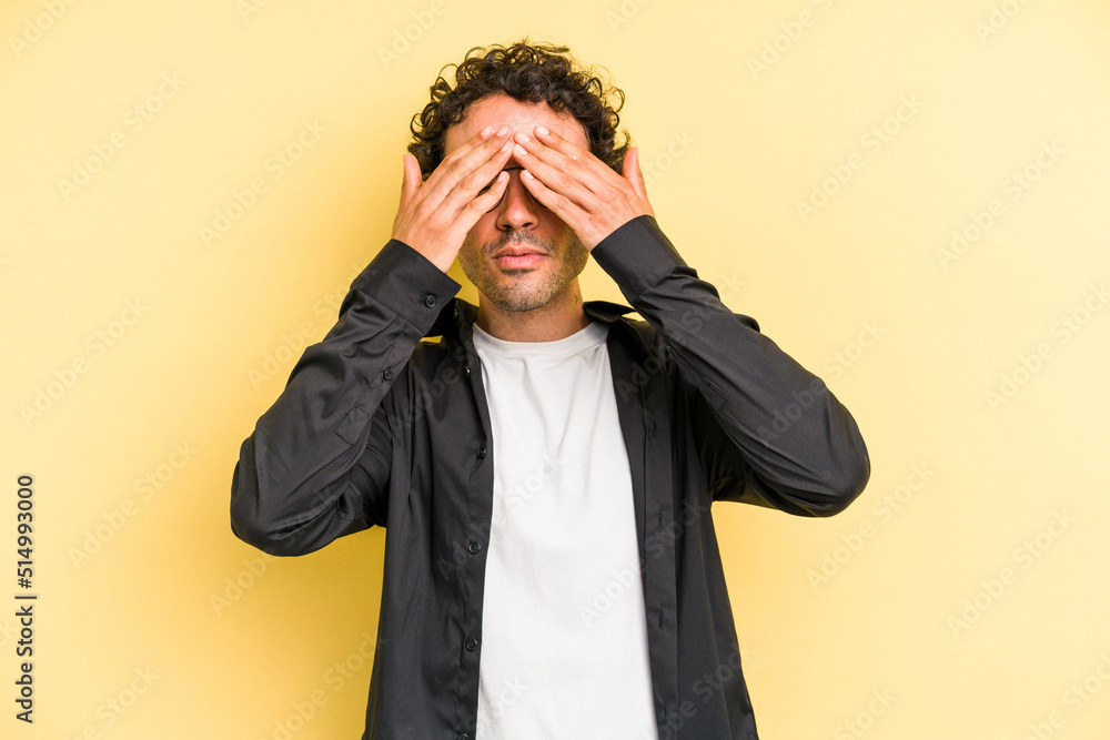 Young caucasian man isolated on yellow background afraid covering eyes with hands. Young caucasian man isolated on yellow background afraid covering eyes with hands.