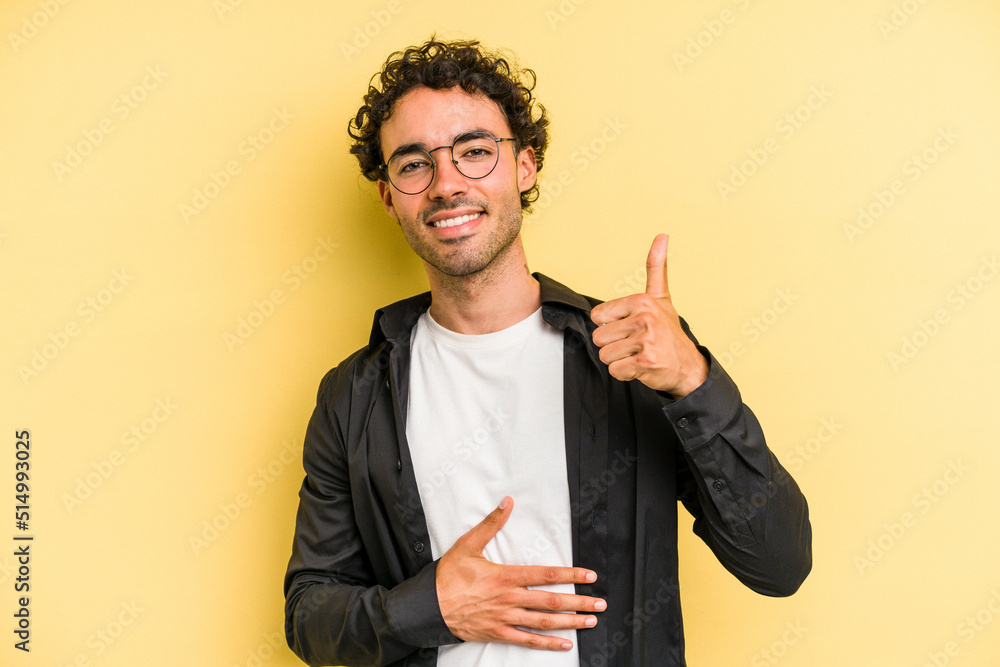 Young caucasian man isolated on yellow background touches tummy, smiles gently, eating and satisfaction concept. Young caucasian man isolated on yellow background touches tummy, smiles gently, eating and satisfaction concept.