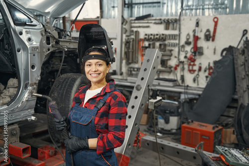 Positive delighted female master holding welding machine