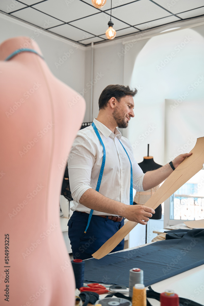 Obraz premium Man couturier works with pattern in a sewing workshop