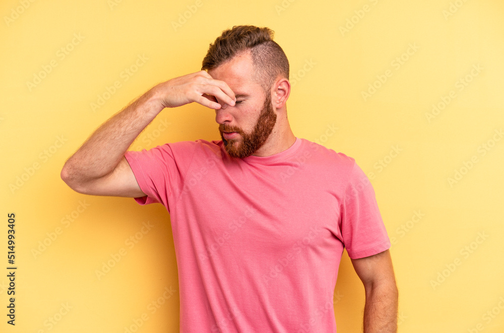 Young caucasian man isolated on yellow background having a head ache, touching front of the face. Young caucasian man isolated on yellow background having a head ache, touching front of the face.