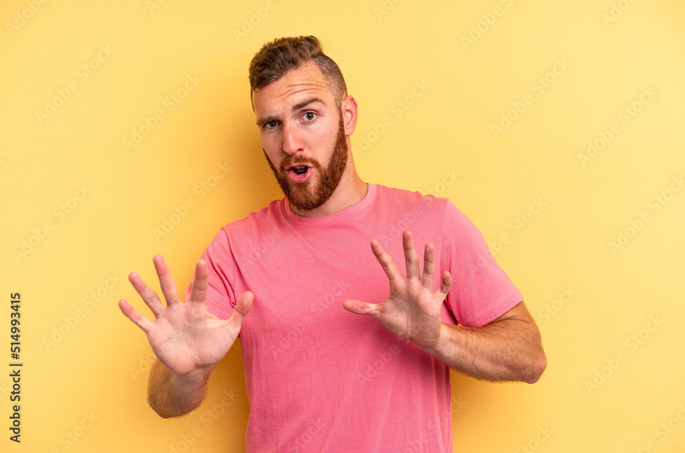 Young caucasian man isolated on yellow background rejecting someone showing a gesture of disgust. Young caucasian man isolated on yellow background rejecting someone showing a gesture of disgust.