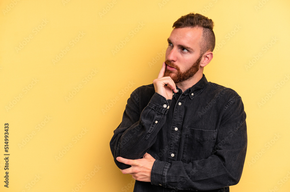 Fototapeta premium Young caucasian man isolated on yellow background relaxed thinking about something looking at a copy space.