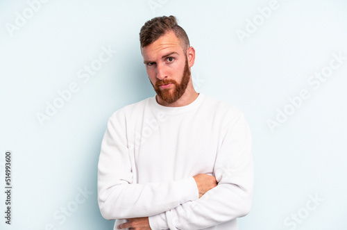 Young caucasian man isolated on blue background suspicious, uncertain, examining you. © Asier