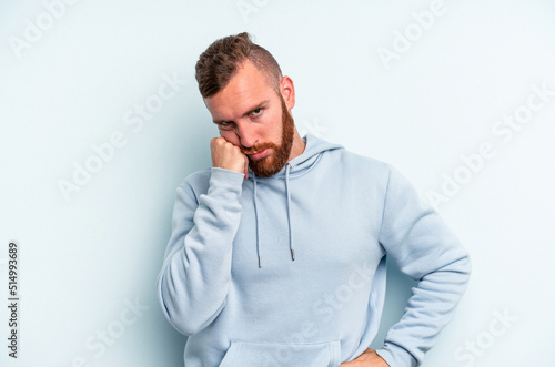 Young caucasian man isolated on blue background tired of a repetitive task.