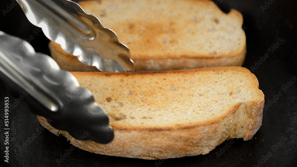 Cooking toasts sliced bread in a frying pan. Chef turns over and toasts