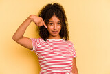 Young Brazilian woman isolated on yellow background person pointing by hand to a shirt copy space, proud and confident