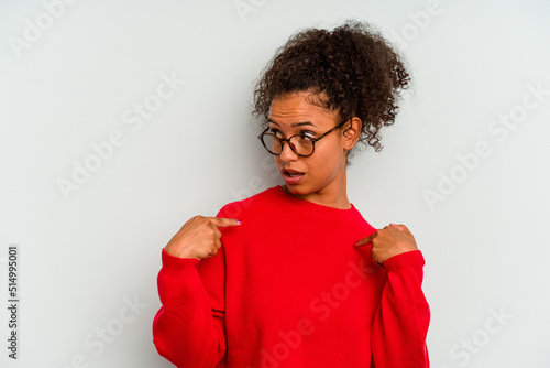 Young Brazilian woman isolated on blue background surprised pointing with finger, smiling broadly.
