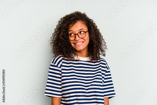 Young Brazilian woman isolated on blue background laughs and closes eyes, feels relaxed and happy.