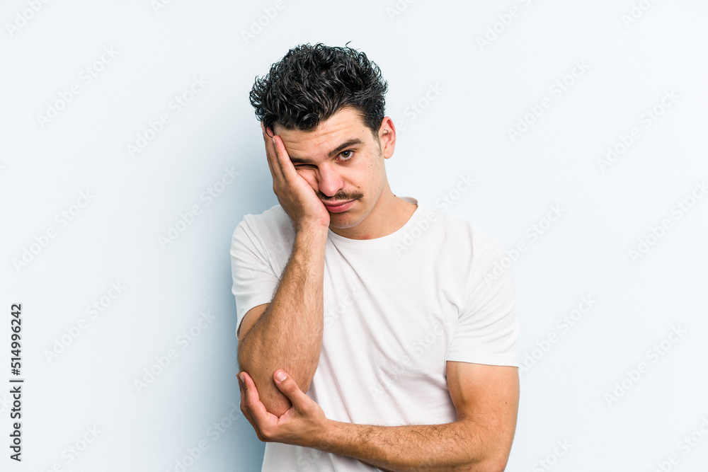 Young caucasian man isolated on blue background who is bored, fatigued and need a relax day.