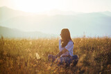 Beautiful Teen Girl sitting in Mountain Golden Field