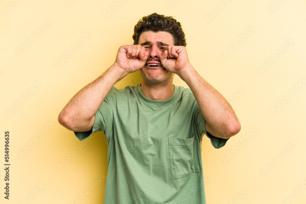 Young caucasian man isolated on yellow background whining and crying disconsolately. Young caucasian man isolated on yellow background whining and crying disconsolately.