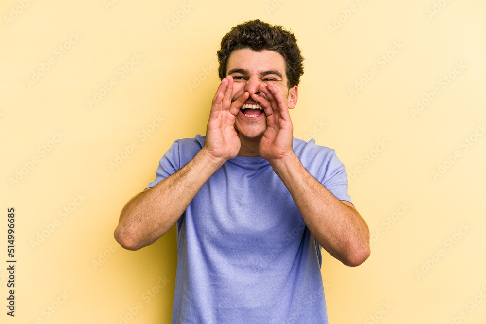 Young caucasian man isolated on yellow background saying a gossip, pointing to side reporting something. Young caucasian man isolated on yellow background saying a gossip, pointing to side reporting something.
