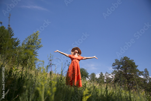 Slow life. Enjoying the little things. spends time in nature in summer. happy middle aged woman wearing an orange dress and straw hat relaxed outdoors. copy space. concept without stress. mental healt