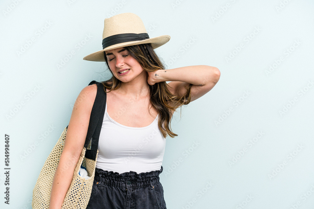 Young caucasian woman holding beach bag isolated on blue background touching back of head, thinking and making a choice. Young caucasian woman holding beach bag isolated on blue background touching back of head, thinking and making a choice.