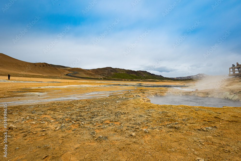 People observe grounds of Hverir geothermal area in the north of Iceland. Steam coming out of hot mud pots emitting sulfur gases. People observe grounds of Hverir geothermal area in the north of Iceland. Steam coming out of hot mud pots emitting sulfur gases.