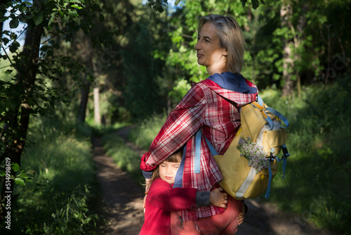 mom and and child daughter with backpack walking in the forest. Staycations  hyper-local travel  family outing  getaway  natural environ. Concept of friendly family. Family spends summer time together
