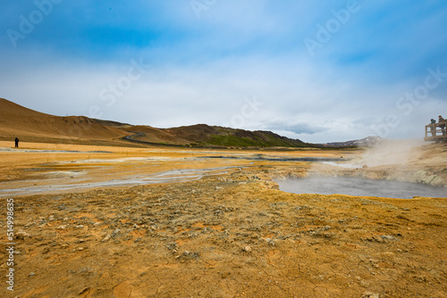 People observe grounds of Hverir geothermal area in the north of Iceland. Steam coming out of hot mud pots emitting sulfur gases.