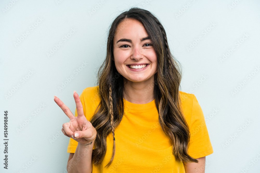 Young caucasian woman isolated on blue background showing victory sign and smiling broadly. Young caucasian woman isolated on blue background showing victory sign and smiling broadly.