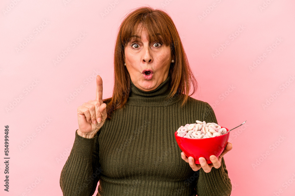 Middle age caucasian woman holding bowl of cereals isolated on pink background having some great idea, concept of creativity. Middle age caucasian woman holding bowl of cereals isolated on pink background having some great idea, concept of creativity.