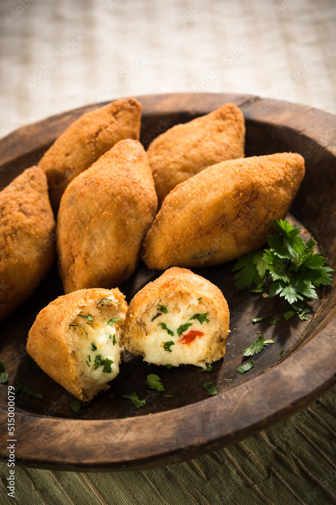 Cheese filled fritters, on a wood plate, with parsley aside