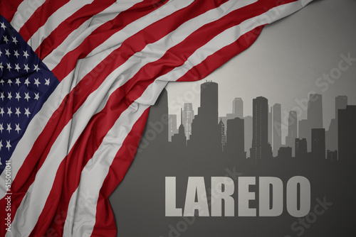 abstract silhouette of the city with text Laredo near waving national flag of united states of america on a gray background. 3D illustration photo