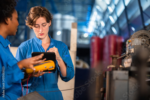 Engineer senior asian man and african woman wearing safety helmet working and checking machine automotive part warehouse. Factory for the manufacture and processing.