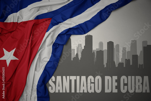 Canvas Print abstract silhouette of the city with text Santiago de Cuba near waving national flag of cuba on a gray background