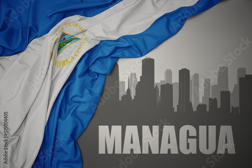 Fototapeta abstract silhouette of the city with text Managua near waving national flag of nicaragua on a gray background