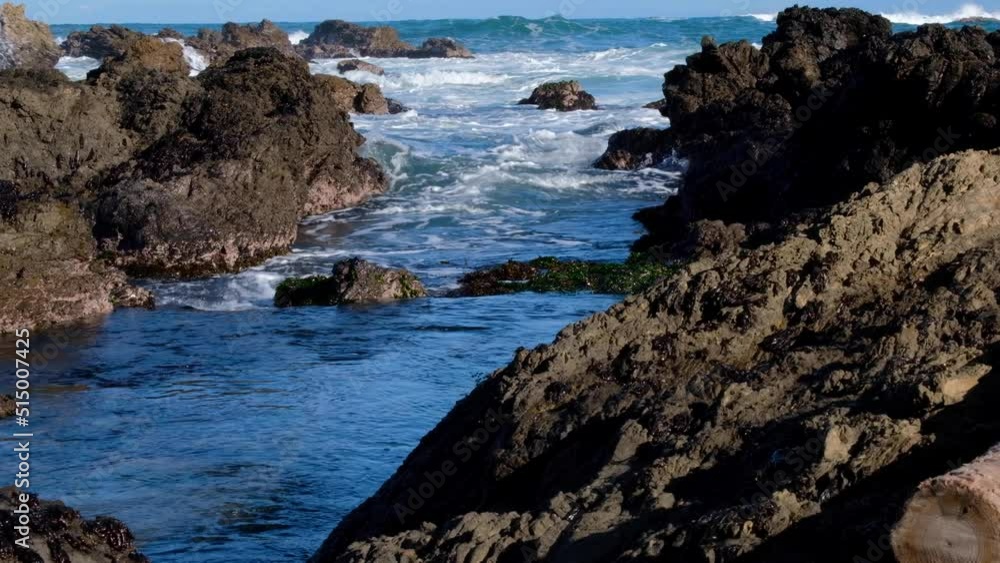 Ocean tide rising and white wash waves rolling into rugged, jagged rock pools at remote coastline in the wilderness Ocean tide rising and white wash waves rolling into rugged, jagged rock pools at remote coastline in the wilderness