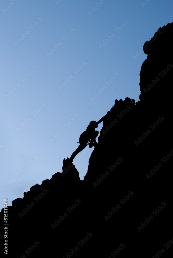 Young woman climbing to the top of the mountain. Concept of self-improvement and motivational goals.