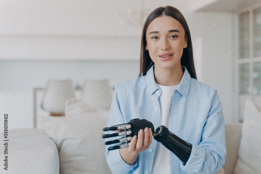 Happy disabled young woman is assembling bionic limb prosthesis. Attractive girl has cyber hand.