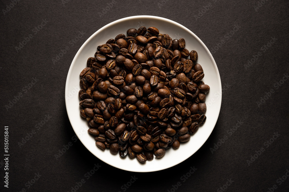 closeup of roasted coffee beans on white plate closeup of roasted coffee beans on white plate
