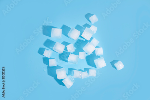 Many ice cubes on a blue background. Top view  flat lay