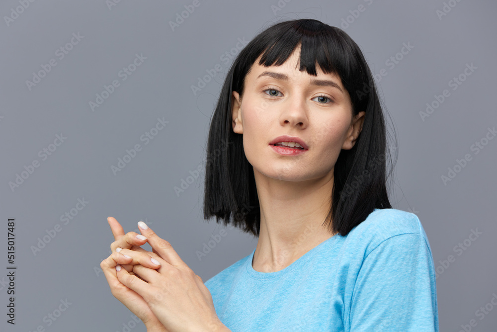 a peaceful woman stands on a dark background in a blue T-shirt joined two hands together, taking them slightly to the side, calmly looking forward a peaceful woman stands on a dark background in a blue T-shirt joined two hands together, taking them slightly to the side, calmly looking forward