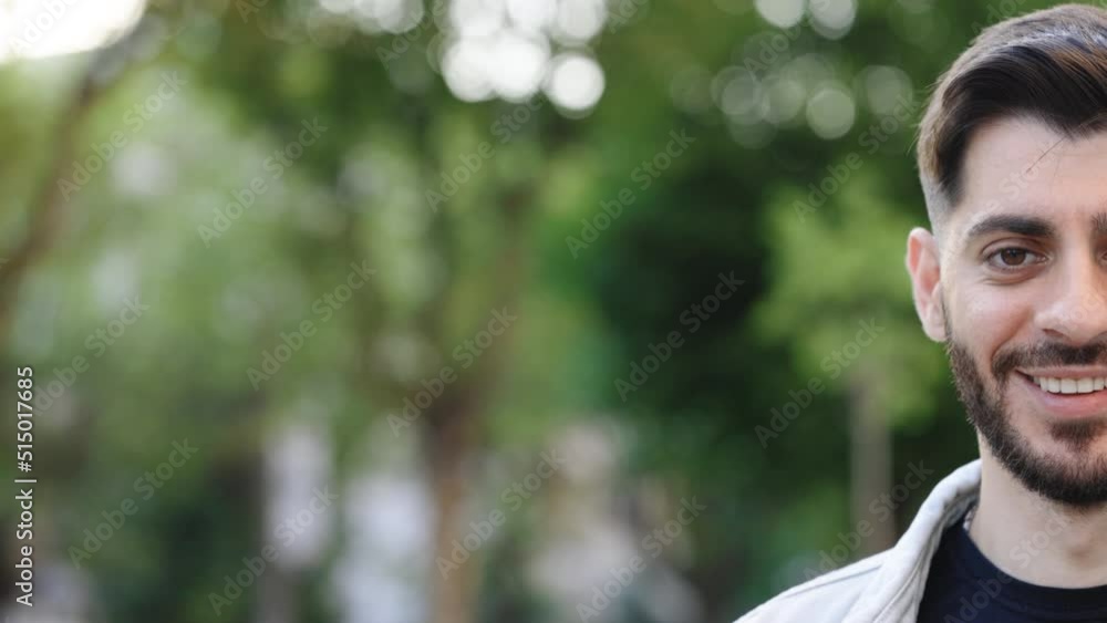 Half face of bearded man with beautiful brown eye while standing outdoors. Sensual guy with trendy hairstyle looking into camera. Portrait of male looking to camera and smiling, with space for text Half face of bearded man with beautiful brown eye while standing outdoors. Sensual guy with trendy hairstyle looking into camera. Portrait of male looking to camera and smiling, with space for text