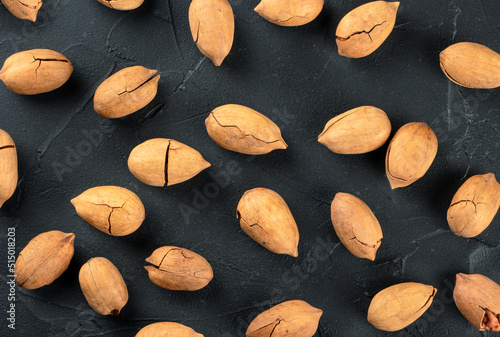 Background of scattered inshell pecans on dark concrete, top view photo