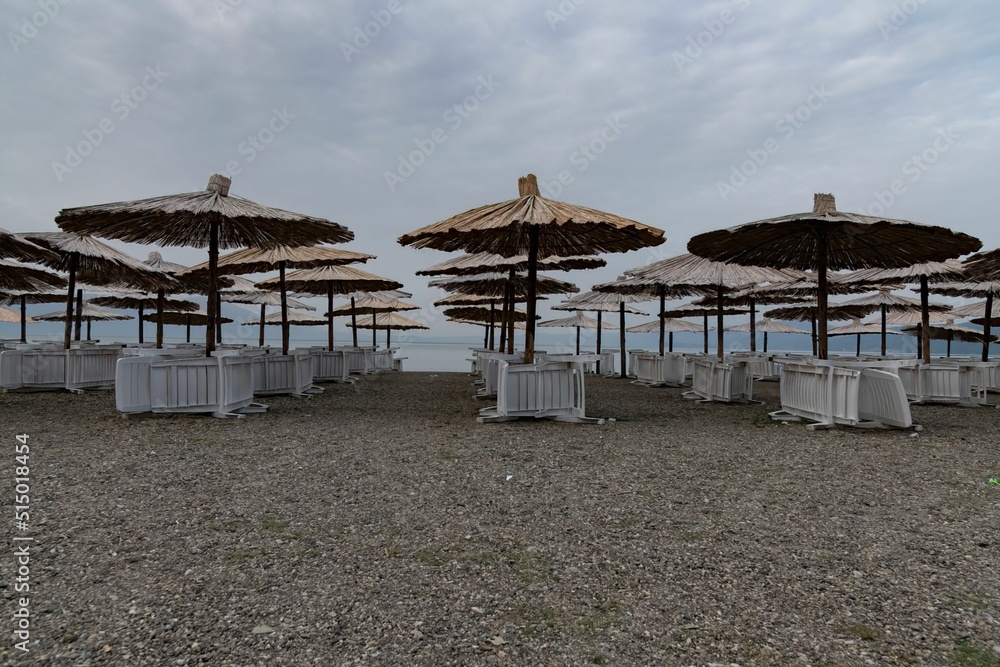 Fototapeta premium chairs and beach umbrellas at an empty sand beach at Lake Ohrid